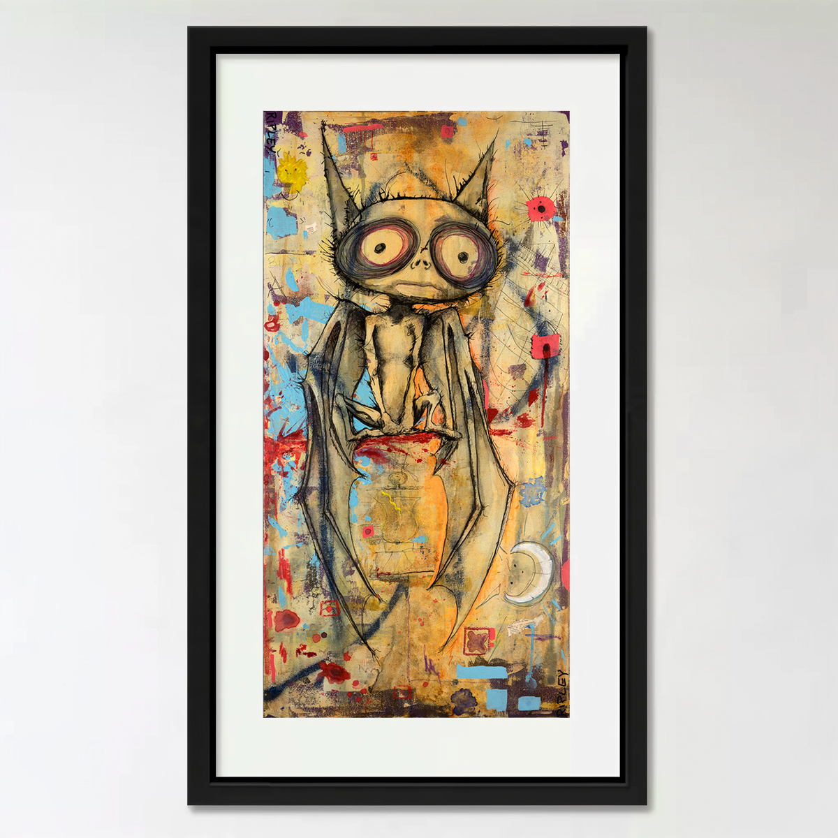 A framed vertical art print featuring a stylized, expressive bat with large eyes and flowing dark drapery, rendered in a multicolored abstract style. The artwork is mounted with a white mat inside a black frame against a light gray wall.