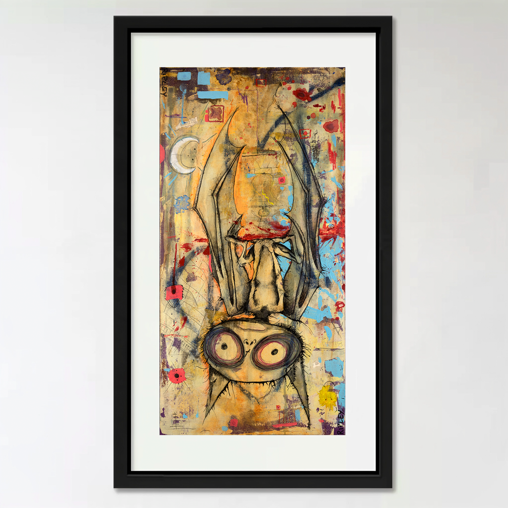 A framed vertical art print featuring a stylized, expressive bat with large eyes and flowing dark drapery, rendered in a multicolored abstract style. The artwork is mounted with a white mat inside a black frame against a light gray wall.