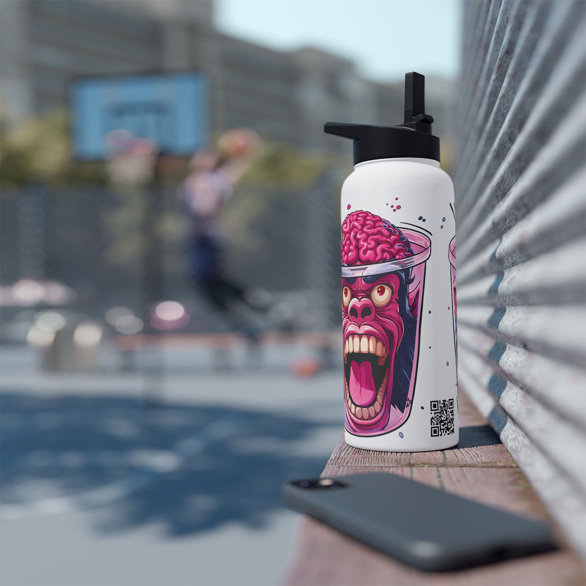 A white insulated water bottle with a black flip-top lid stands on a wooden ledge outdoors. The bottle features a colorful graphic of a screaming face with a pink brain on its head.