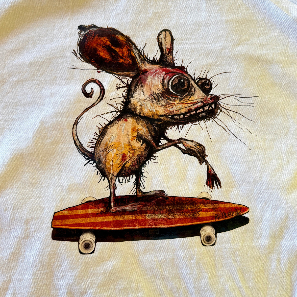 A close-up of a white fabric surface featuring a whimsical illustration of a small, hairy mouse balancing on a red-orange skateboard.