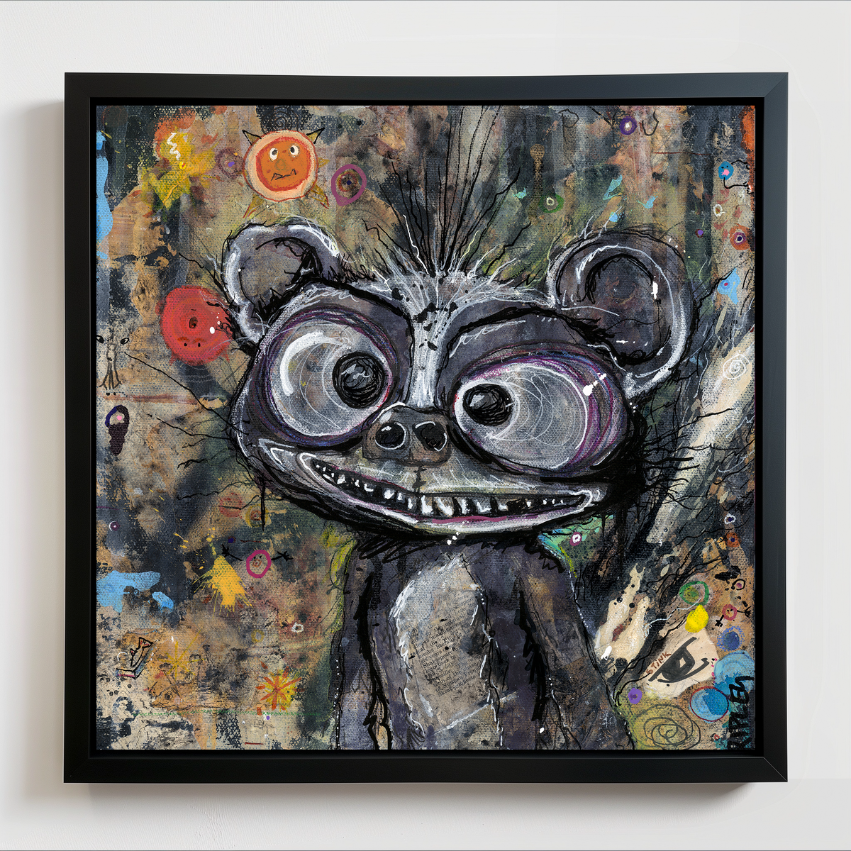 A framed abstract painting of a stylized skunk character with large eyes and a wide grin, shown against a textured multicolor background. The artwork is housed in a black frame and hangs on a light wall.