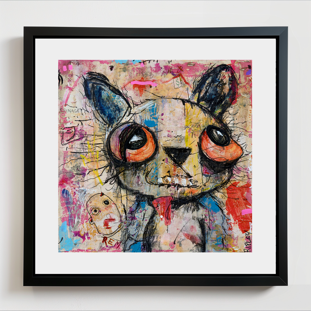 A framed abstract art print featuring a stylized teddy bear face with large orange eyes, painted in a colorful graffiti-style style. The artwork is presented with a white mat and a black frame against a light gray wall.