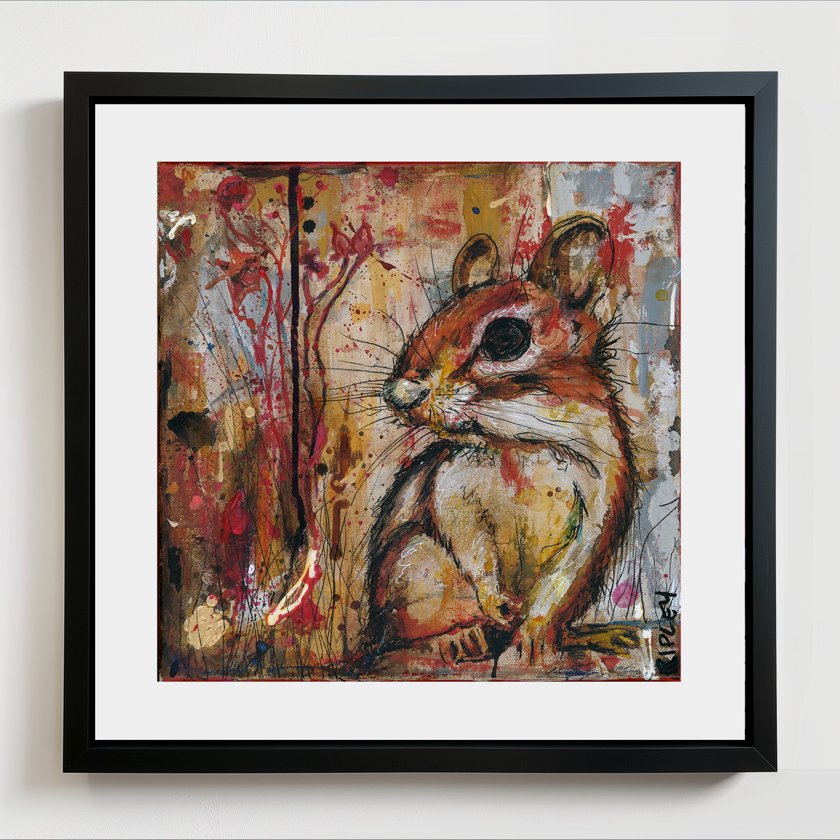 A framed art print featuring a painted chipmunk, set against an abstract multicolor background with red, yellow, and gray paint splatters. The artwork is matted with a wide white border and enclosed in a simple black frame, shown hanging on a light gray wall.