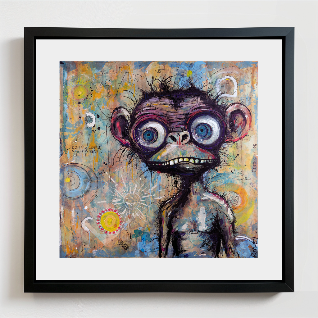 A framed abstract art print featuring a stylized, furry chimpanzee with large blue eyes and a wide grin, set against a colorful background of yellow, blue, and orange tones. The artwork is matted in white and enclosed in a black frame, hanging on a light gray wall.